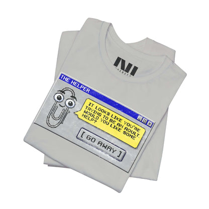 folded Heather athletic grey t-shirt featuring a retro pixelated computer pop-up window graphic with a cartoon paperclip assistant. The text within the window reads, "IT LOOKS LIKE YOU'RE TRYING TO BE AN ADULT. WOULD YOU LIKE SOME HELP?" followed by a button that says "[ GO AWAY ]" #Athletic Heather