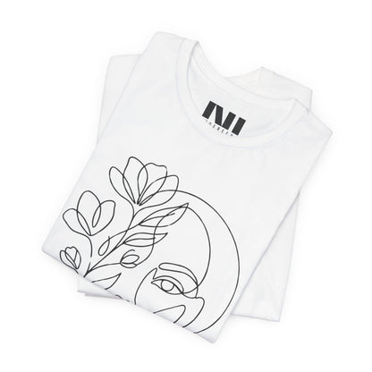 Folded White graphic t-shirt featuring a minimalist black continuous line art design of a woman's face blooming with floral botanical elements. MOEBEER tees #White