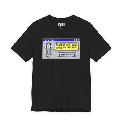 Black t-shirt featuring a retro pixelated computer pop-up window graphic with a cartoon paperclip assistant. The text within the window reads, "IT LOOKS LIKE YOU'RE TRYING TO BE AN ADULT. WOULD YOU LIKE SOME HELP?" followed by a button that says "[ GO AWAY ]" #Black