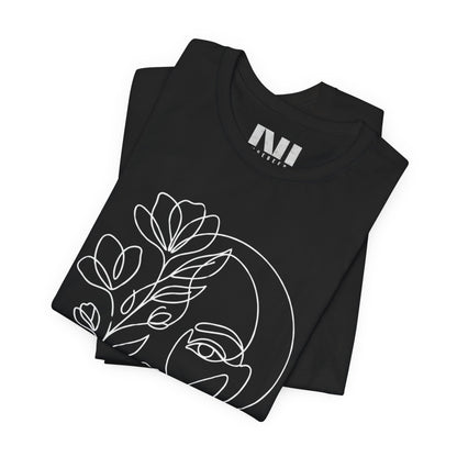 Folded Black graphic t-shirt featuring a minimalist black continuous line art design of a woman's face blooming with floral botanical elements. MOEBEER tees #Black