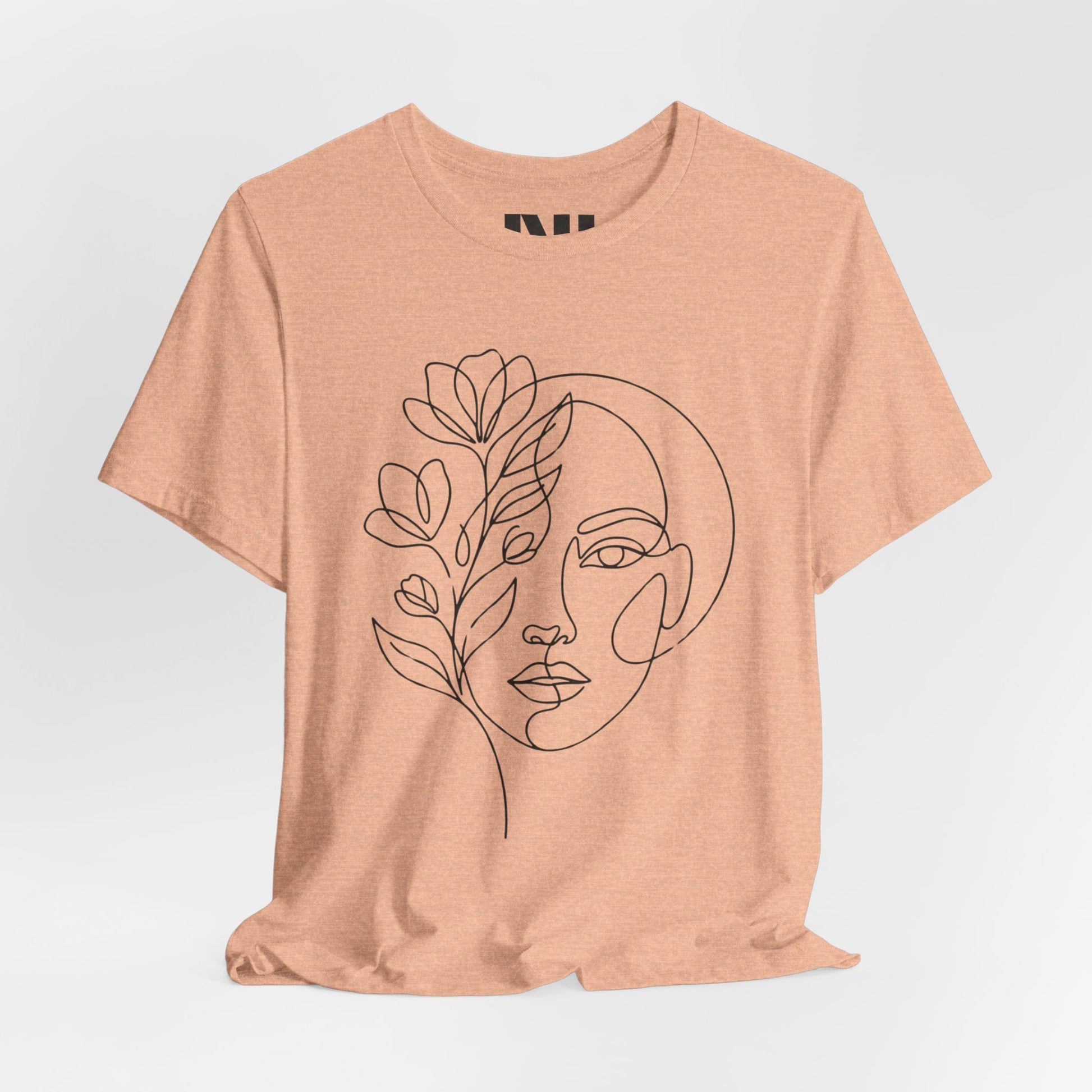 Heather Peach graphic t-shirt featuring a minimalist black continuous line art design of a woman's face blooming with floral botanical elements. #Heather Peach