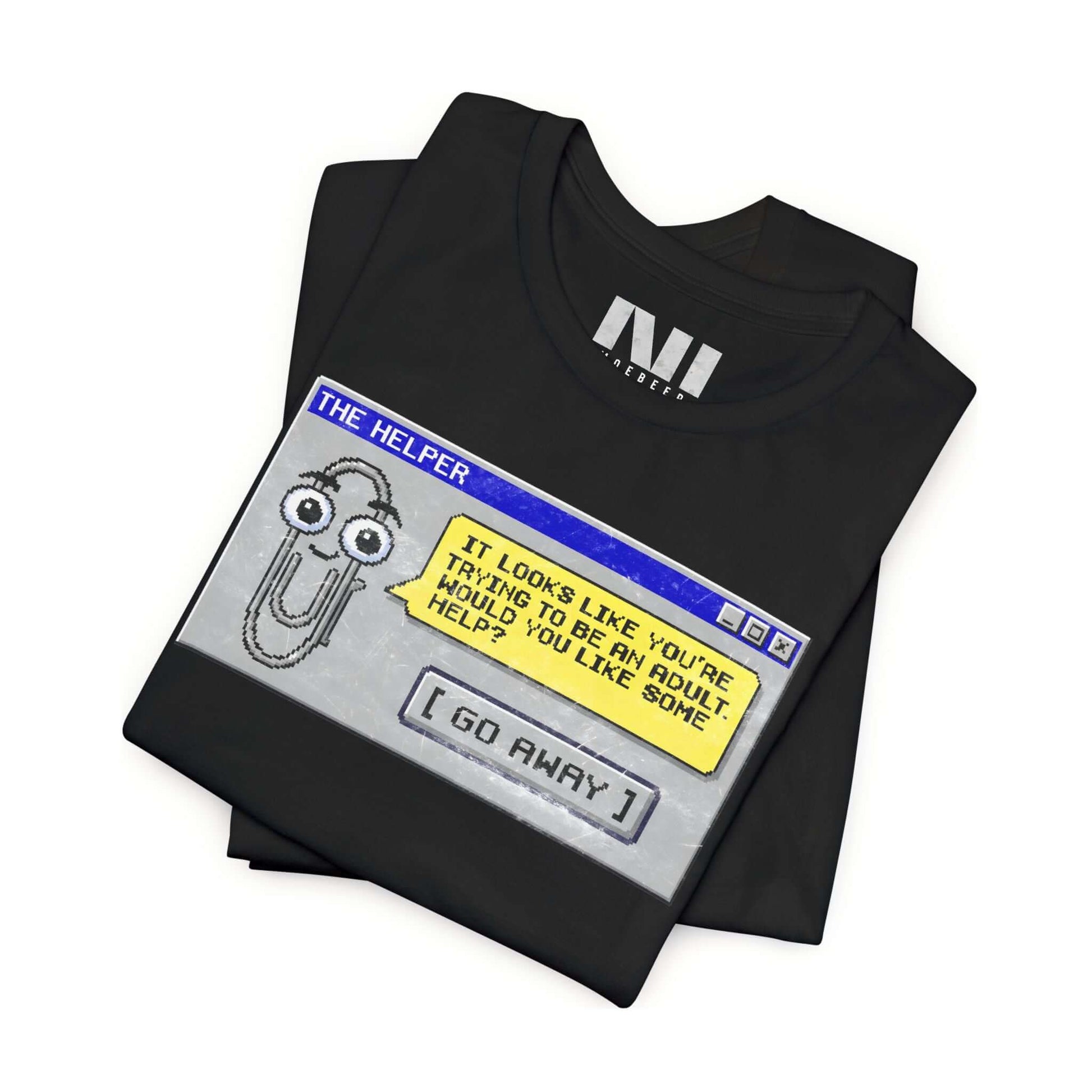 folded Black t-shirt featuring a retro pixelated computer pop-up window graphic with a cartoon paperclip assistant. The text within the window reads, "IT LOOKS LIKE YOU'RE TRYING TO BE AN ADULT. WOULD YOU LIKE SOME HELP?" followed by a button that says "[ GO AWAY ]" #Black