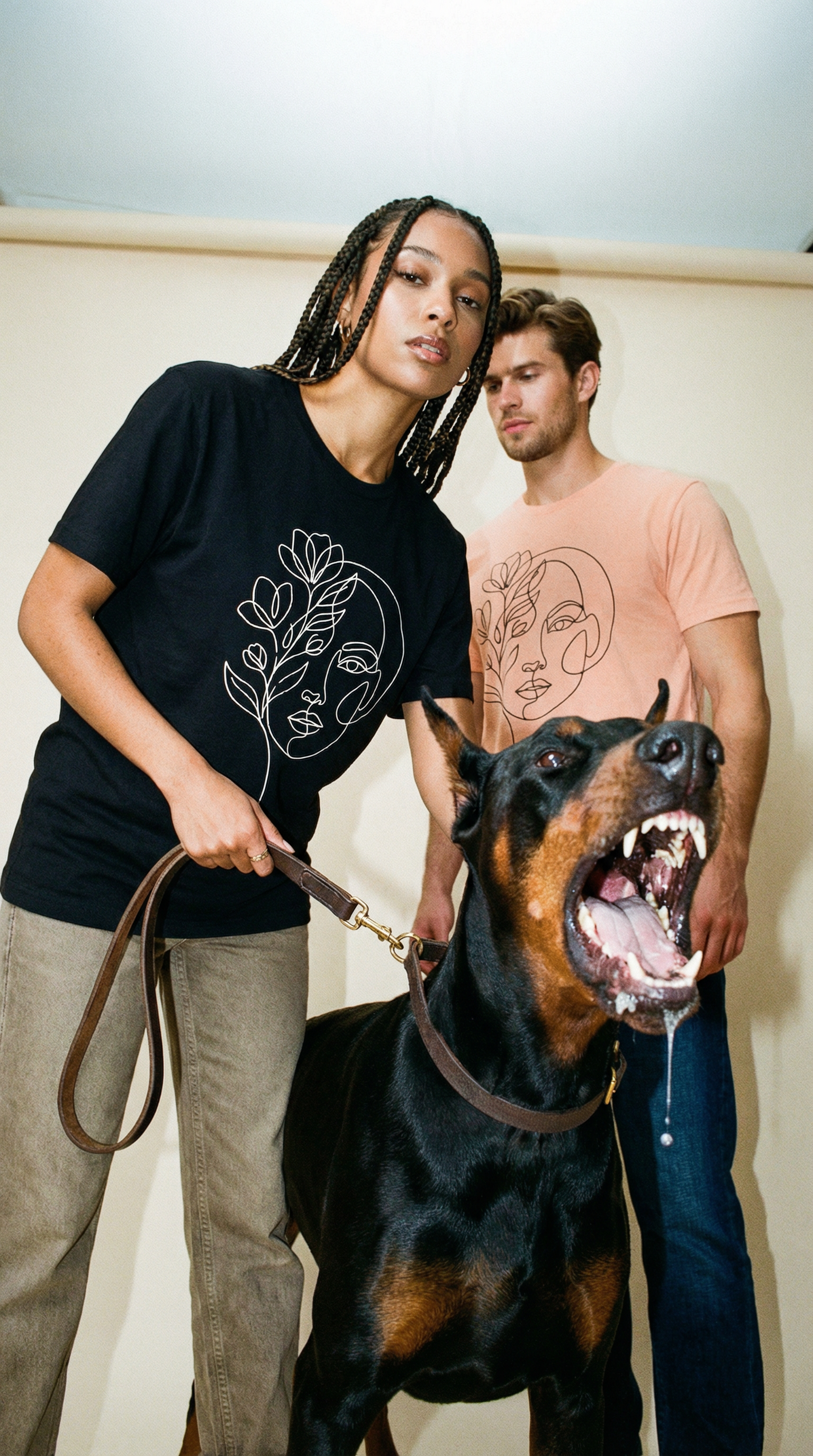 street wear MOEBEER T-shirt Two people standing with a Doberman Pinscher dog indoors.